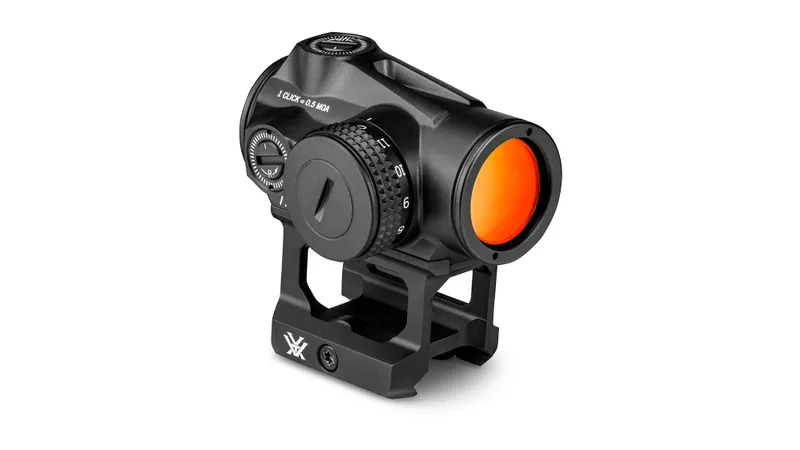 The Vortex Triumph 2MOA Red Dot features a black finish, adjustment dials, and an orange-tinted lens. Mounted on a tactical rail base, it is shown at a three-quarter angle against a white background.