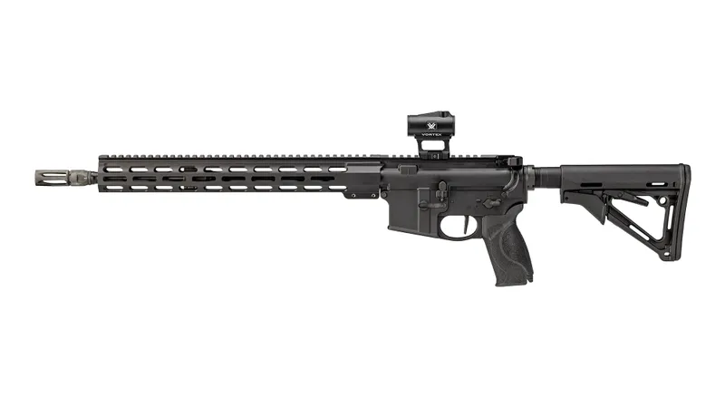 A black semi-automatic rifle with a long barrel, adjustable stock, and rail system features a Vortex Triumph 2MOA Red Dot sight in its side profile, displayed on a white background.