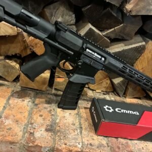 A MAPS-AP22 .22LR AR15 Rifle—fully upgraded and match ready—rests on a brick hearth in front of stacked firewood, with a red and black CMMG box labelled “Stripped Lower” placed nearby.